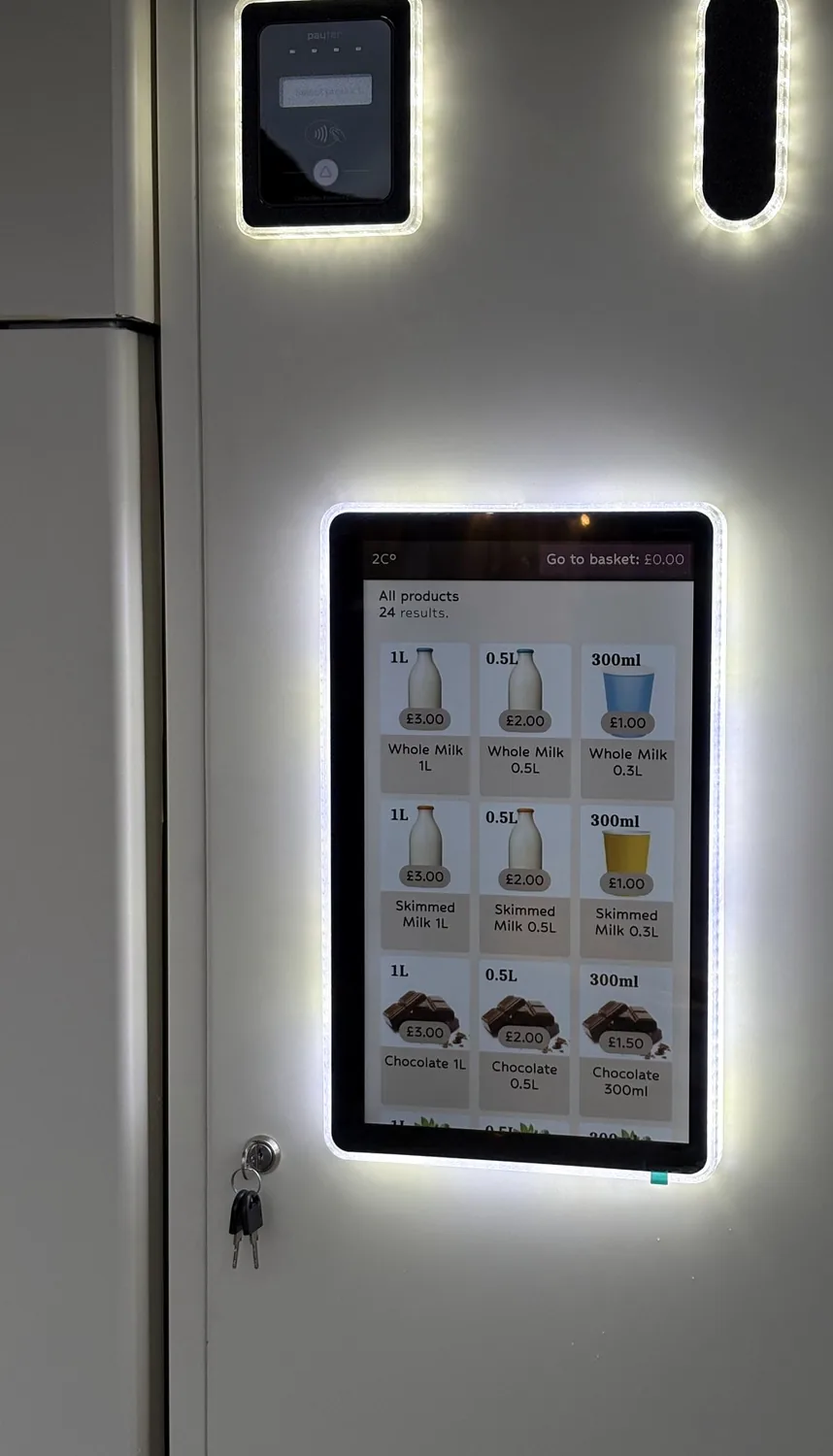 Close-up of the machine's touchscreen menu showing milk and chocolate milkshake options, with the payment reader above